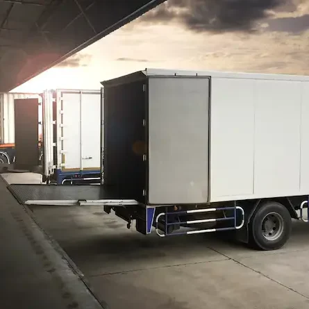 Reefer trucks with their cargo compartments open at a warehouse loading dock.