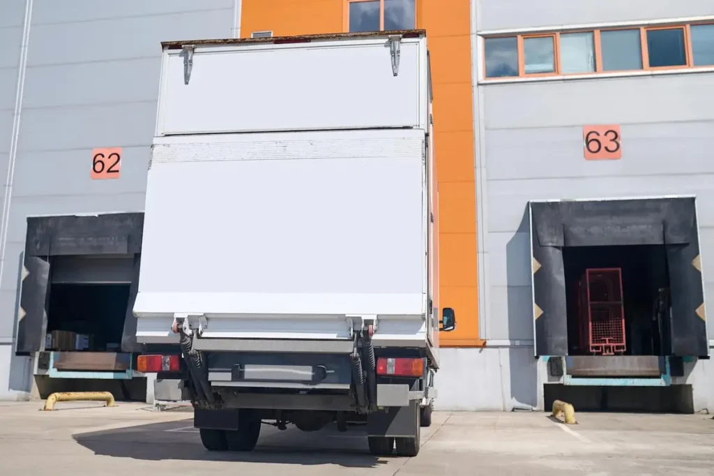 The back view of a refrigerated truck at a warehouse loading dock.